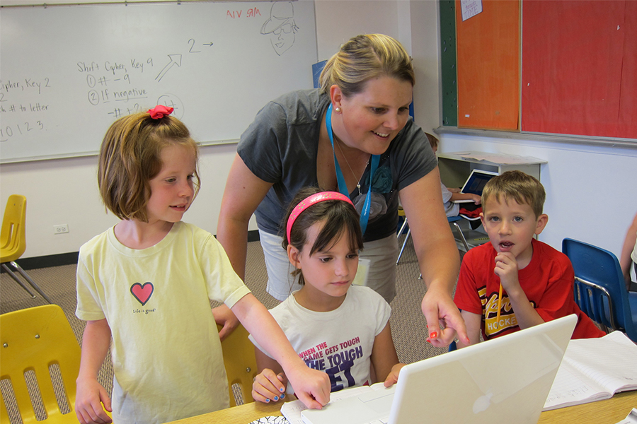 three students with teacher on computer