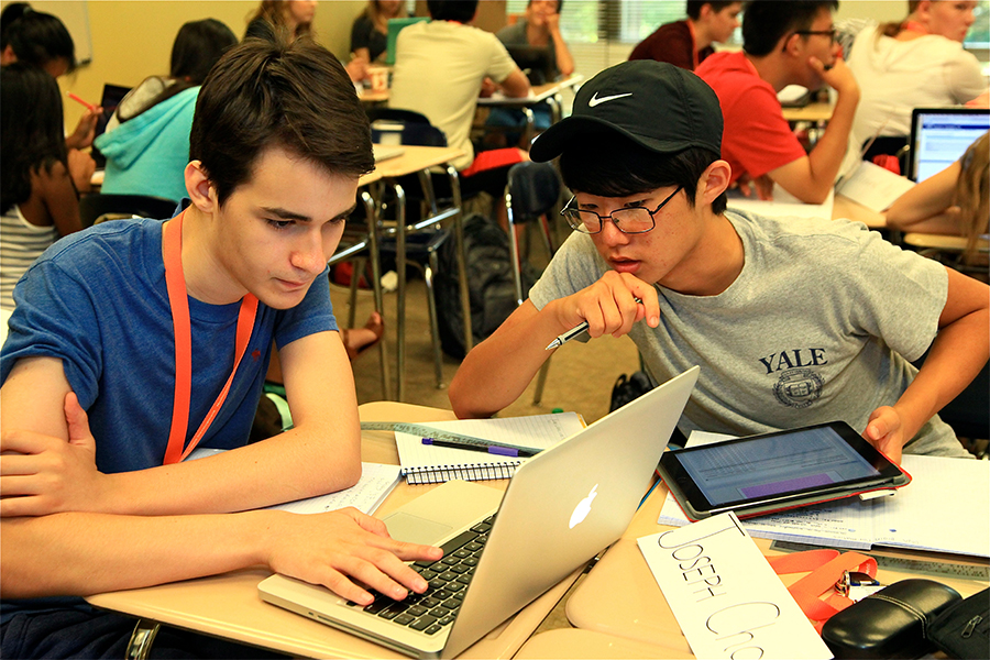 two high school boys working on a class project with computer