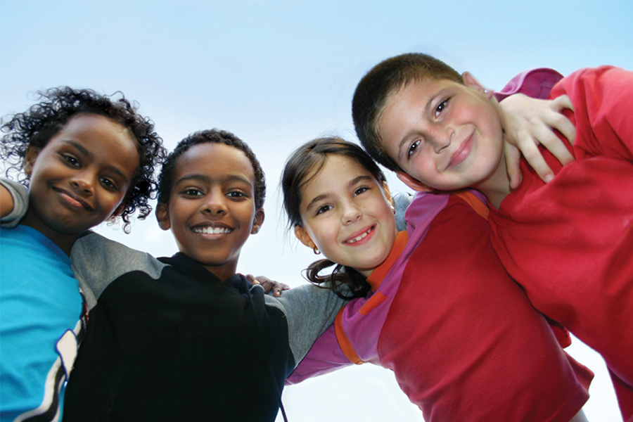 four elementary school students in a huddle smiling at the cameral