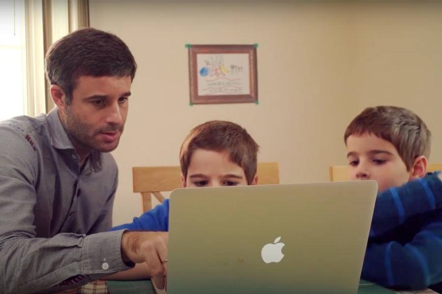 two elementary school boys working with father on computer
