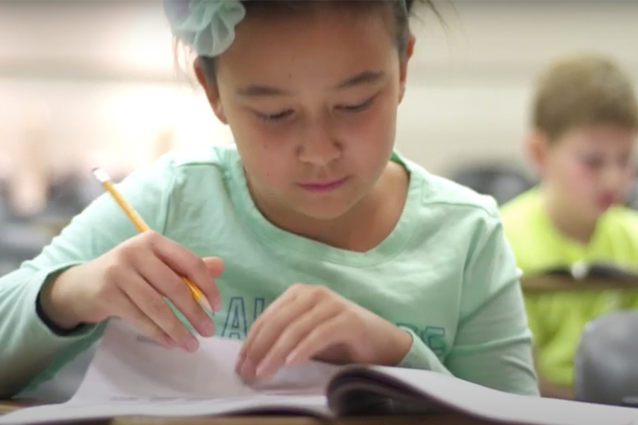 elementary school girl taking a paper and pencil test