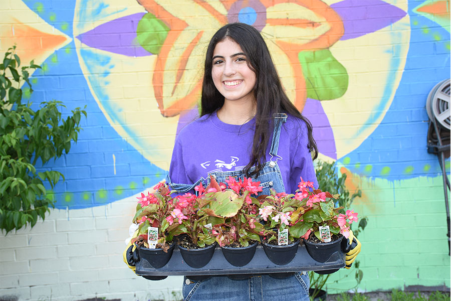 girl smiling and holding flowers, mural behind her