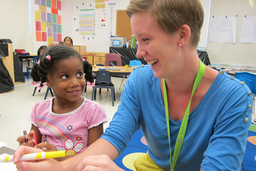 young girl sitting next to teacher