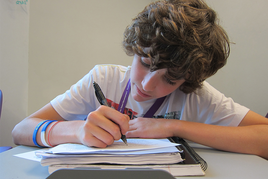 middle school boy writing at desk