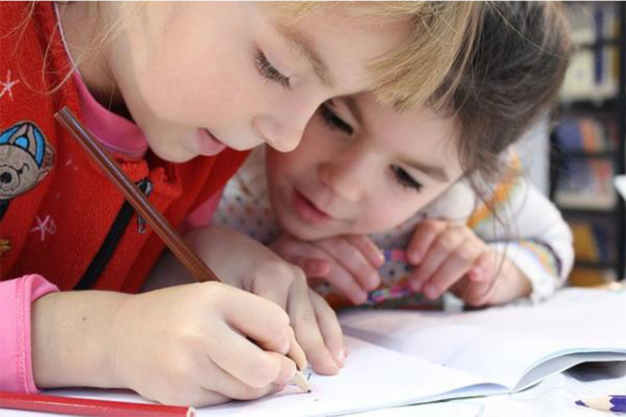 two young children drawing close up of faces