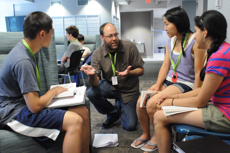 teacher with three students discussing writing