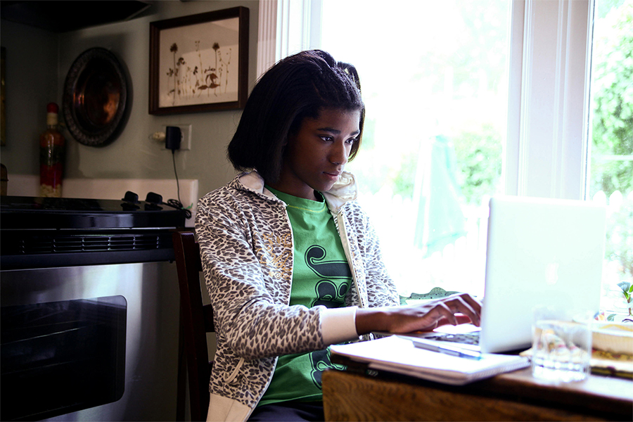 high school girl working at home on laptop