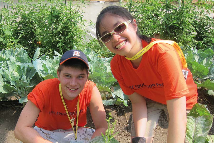 two high school students working in urban garden smiling at camera