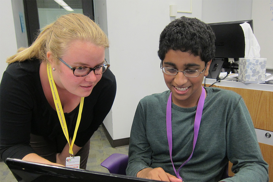 high school teacher and student talking and working on computer