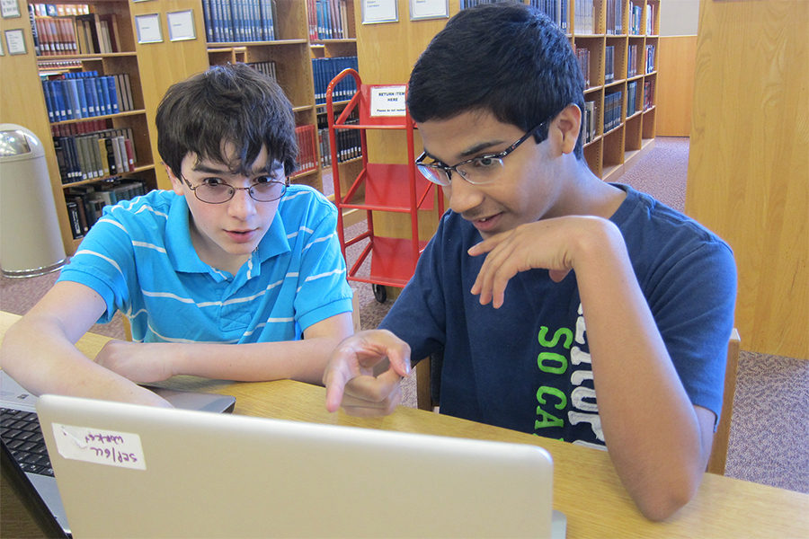 two boys in libarary on laptop