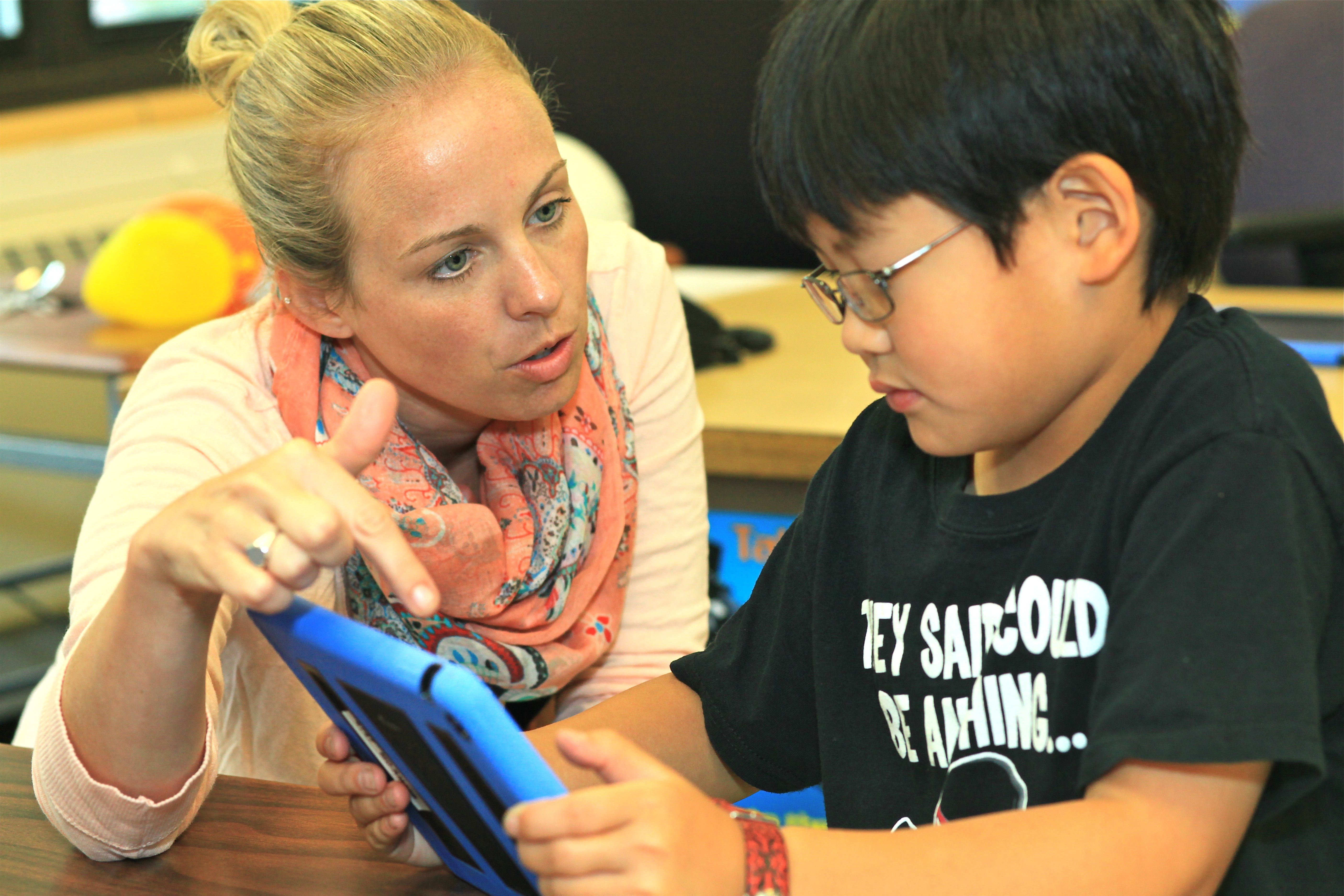 female teacher with elementary student workon on tablet