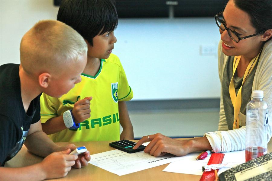 two elementary school boys with teacher working on calculator