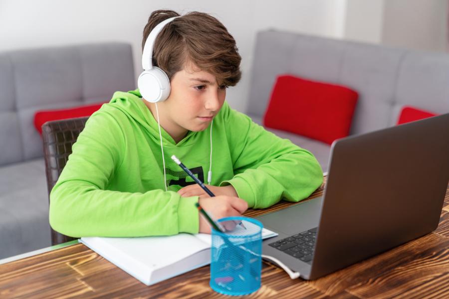 middle school boy with headphones working on laptop computer