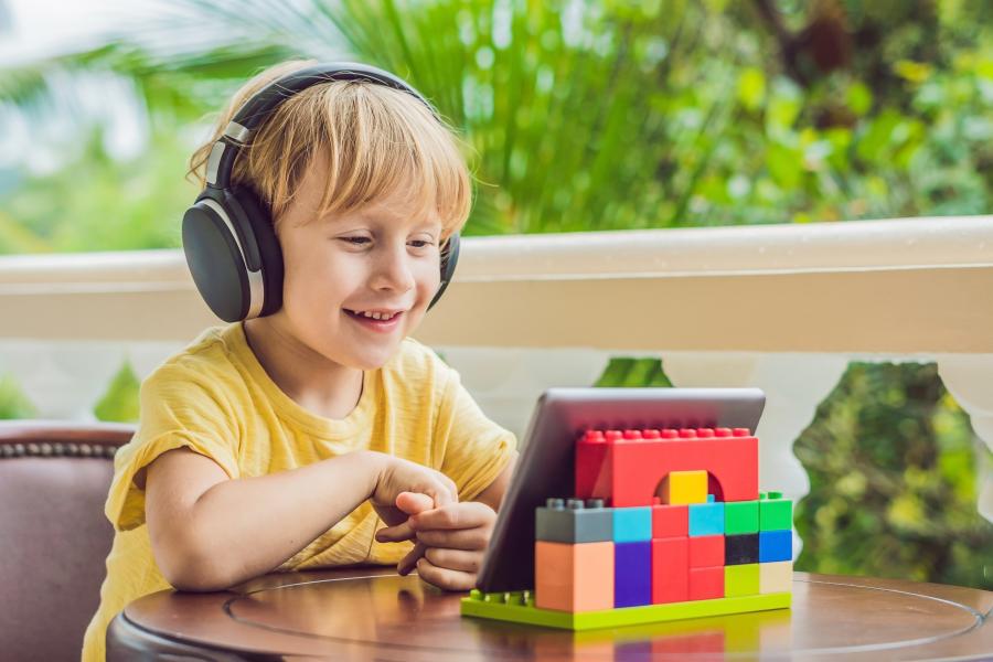 young child with headphones working independently on iPad