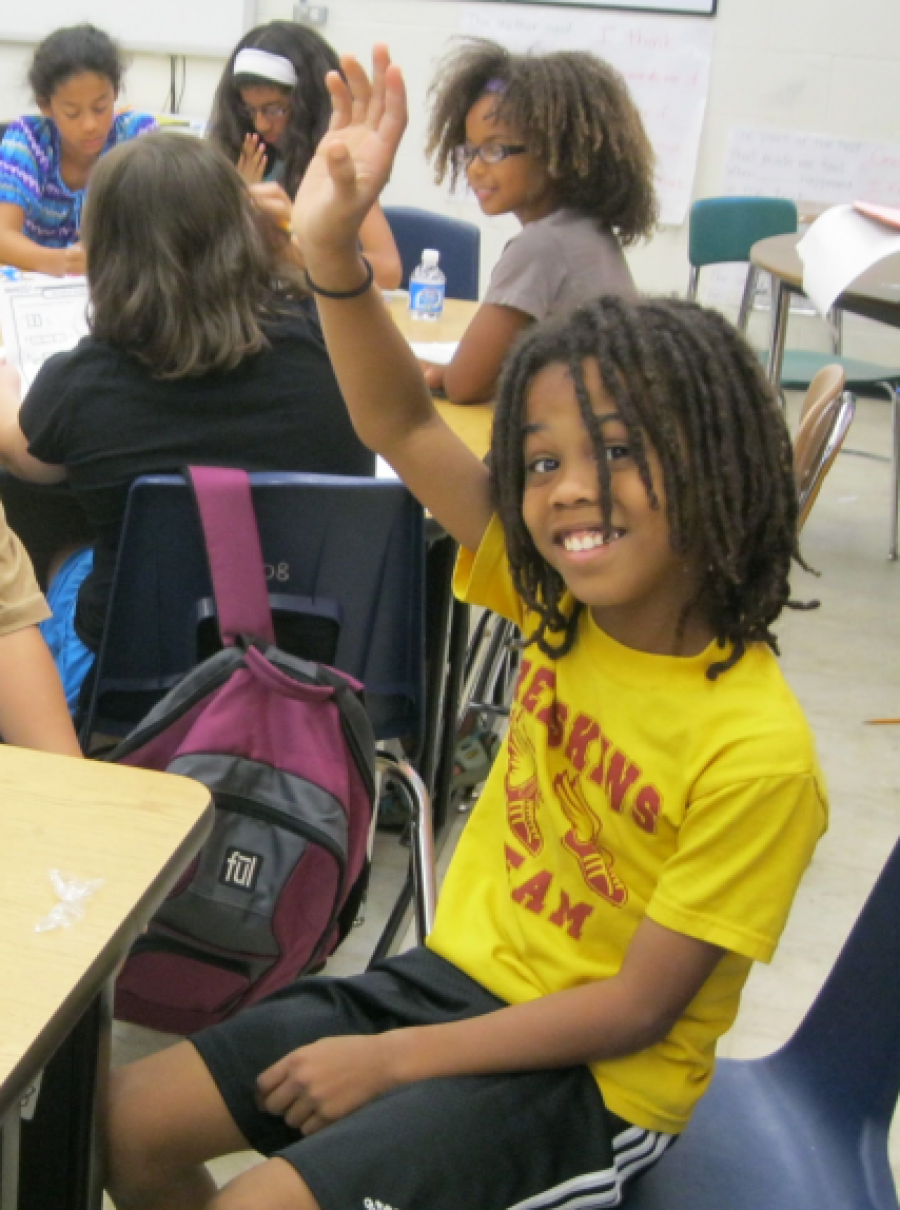 young boy in class raising his hand