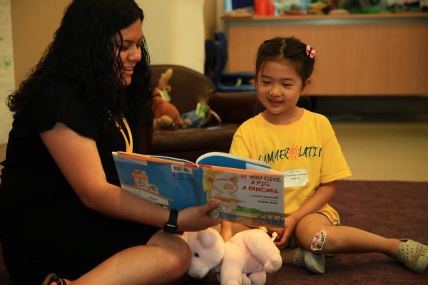 young girl with teacher reading book