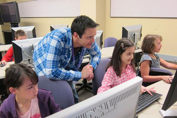 students with male teacher at computers