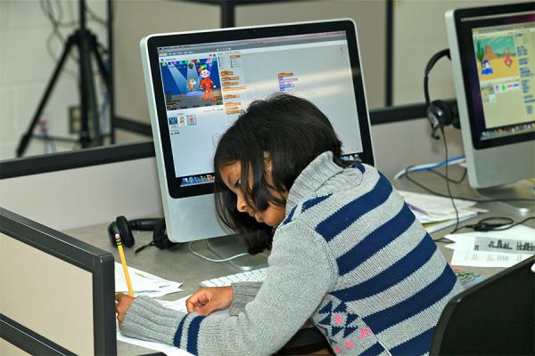 elementary school girl writing and working on desktop computer