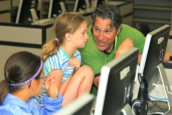 Elementary school students working on computer with teacher