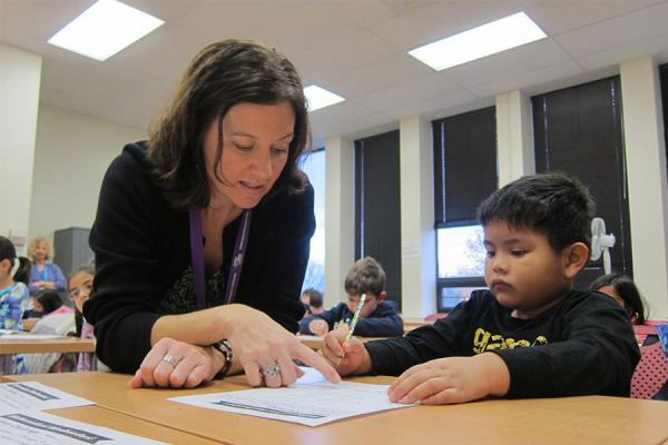 teacher with young child at desk writing