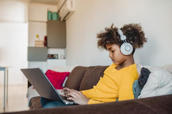 middle school boy working on computer on his couch 