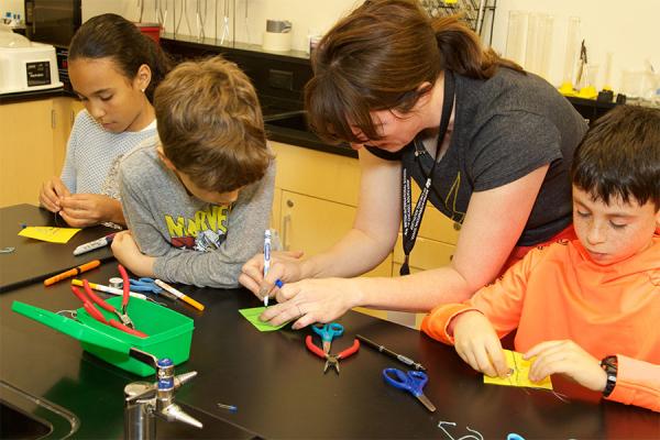 Three elementary school students working on project with teacher