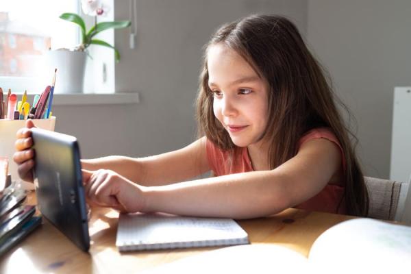 young girl at home at desk working on tablet