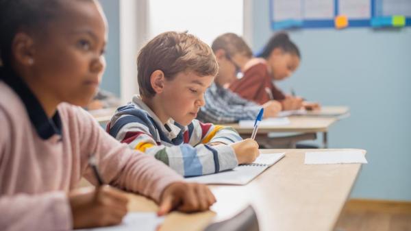 diverse group of elementary school students in a classroom taking notes